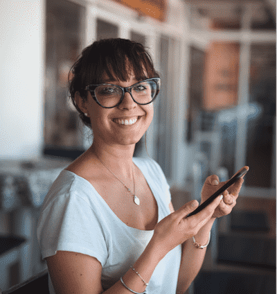 Woman smiling and holding her cell phone Woman smiling and holding her cell phone